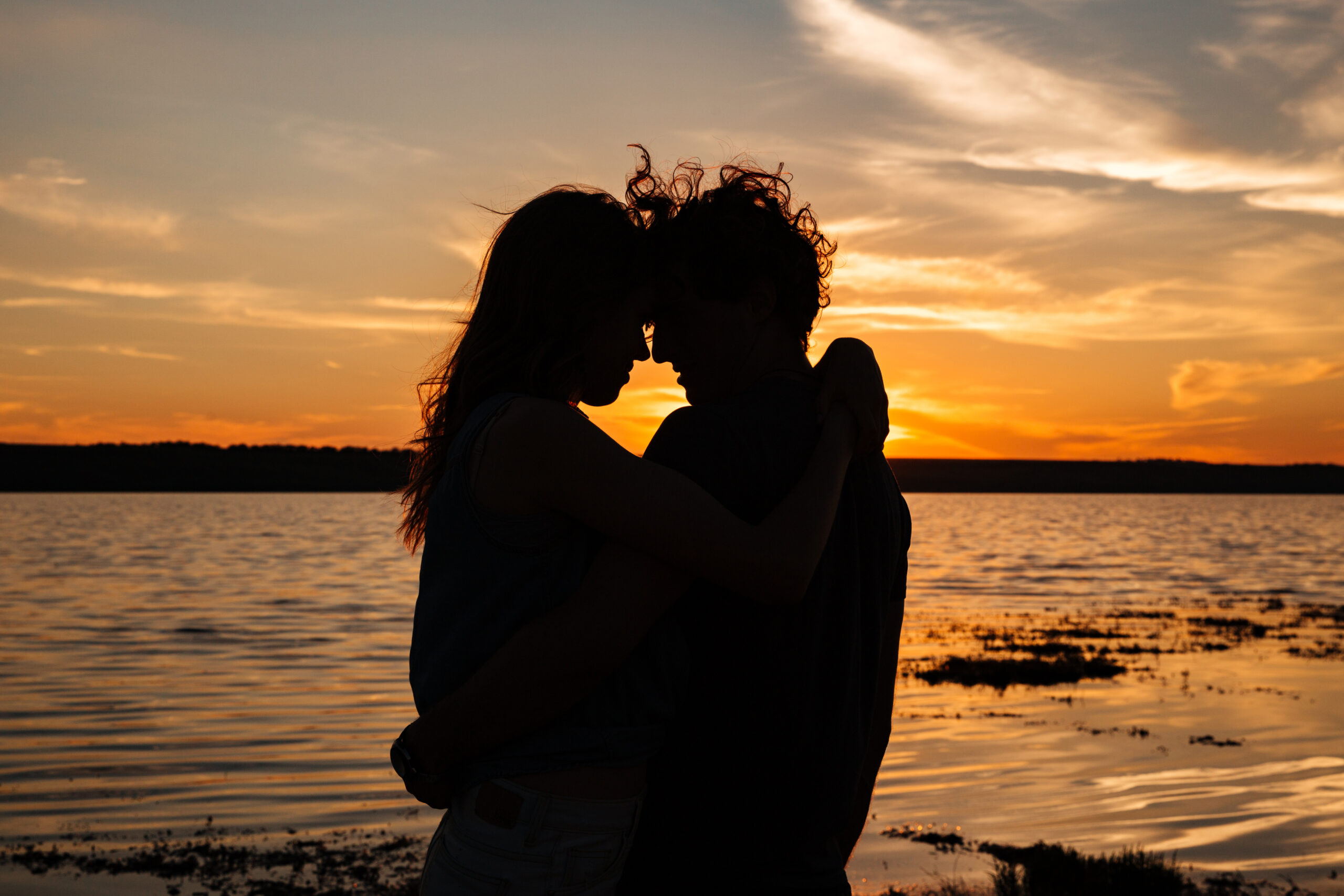 graphicstock two young lovers standing on a beach and looking at each other on sunset background BOSbY57H3x scaled